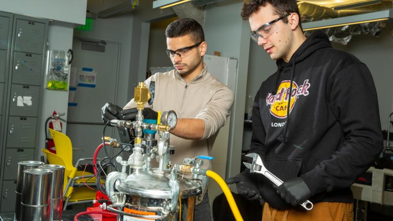 MIT engineers Aly Kombargi (left) and Niko Tsakiris (right) work on a new hydrogen reactor, designed to produce hydrogen gas by mixing aluminum pellets with seawater.