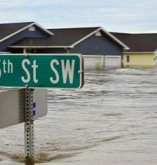 A street sign and houses are underwater due to flooding.