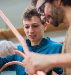 Rising MIT sophomore Sam Packman (left) and his advisor Nicolo Riva, a postdoc at the MIT Plasma Science and Fusion Center, examine a VIPER cable, a special type of high-temperature superconducting cable that holds promise for use in fusion reactors. 