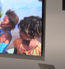 Photo of Professor Carpenter speaking about an image of young children drinking from a plastic bottle filled with polluted water.