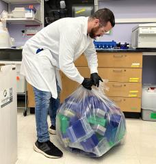 Normand Desrochers, MIT EHS technician, picks up pipette tip boxes and conical tube racks to be recycled. 